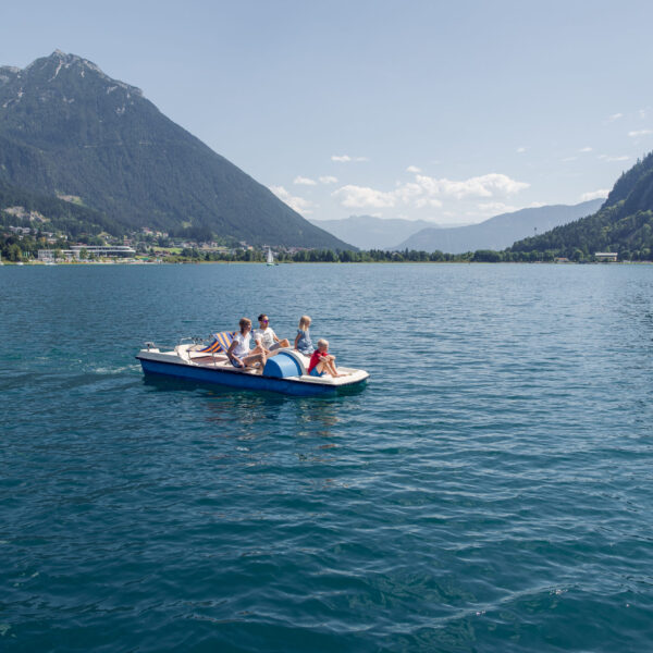 Eine Familie macht sich mit dem Tretboot auf Erkundungstour am Achensee und genießt dabei die Aussicht. /// A family takes a pedal boat out on Lake Achensee and enjoys the gorgeous view.